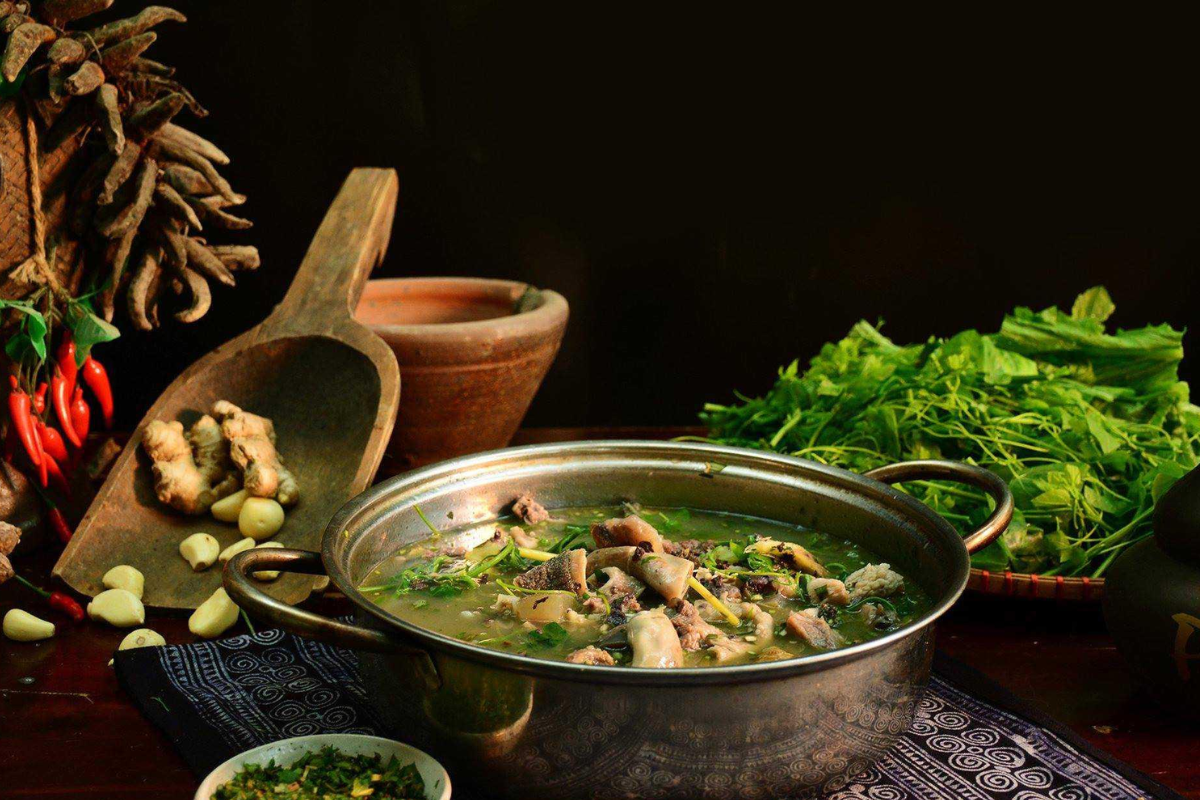 A bowl of thắng cố with herbs and spices